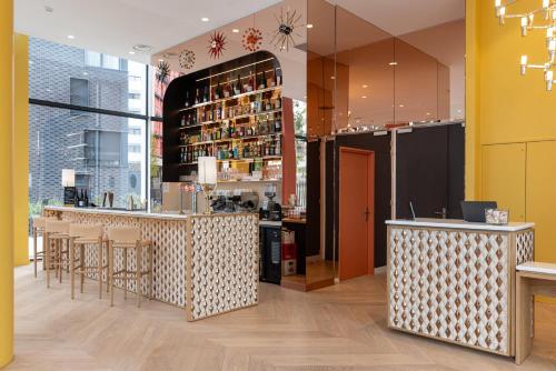 a restaurant with a bar with stools at Hôtel Kyriad Prestige Paris Asnieres in Asnières-sur-Seine