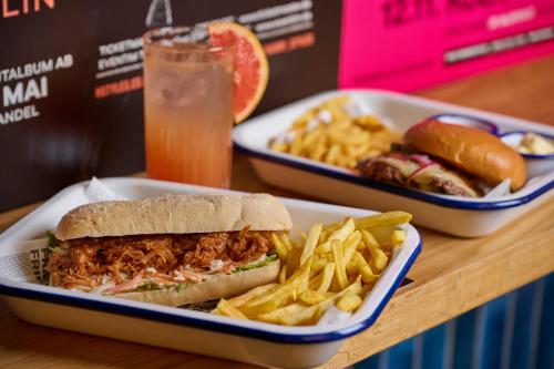 a sandwich and french fries on a table with a drink at Generator Berlin Alexanderplatz in Berlin