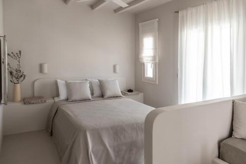 a white bedroom with a bed and a window at Om Living Milos in Pollonia