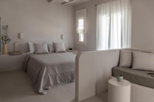 a white bedroom with a bed and a couch at Om Living Milos in Pollonia