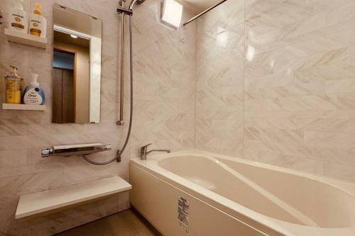 une salle de bain blanche avec une baignoire et un miroir dans l'établissement 天王寺令康民泊5ｆ, à Osaka