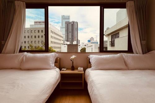 deux lits dans une chambre avec une grande fenêtre dans l'établissement 天王寺令康民泊5ｆ, à Osaka