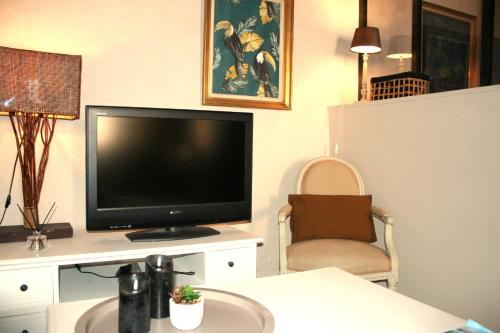 a living room with a flat screen tv and a chair at Appartement EMMA Quartier historique à 400m de la mer in Saint-Raphaël