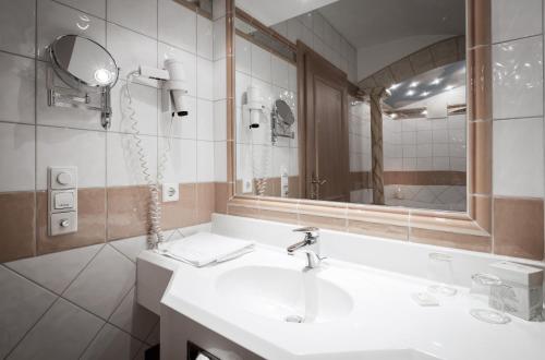 a bathroom with a sink and a mirror at Hotel Rigele Royal Superior in Obertauern