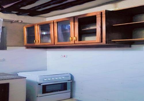 a kitchen with a stove and wooden cabinets at Mlagala Room and Aparment Zanzibar 3 in Ngambo