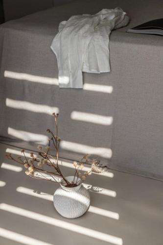 a white vase with a plant in a room at Om Living Milos in Pollonia