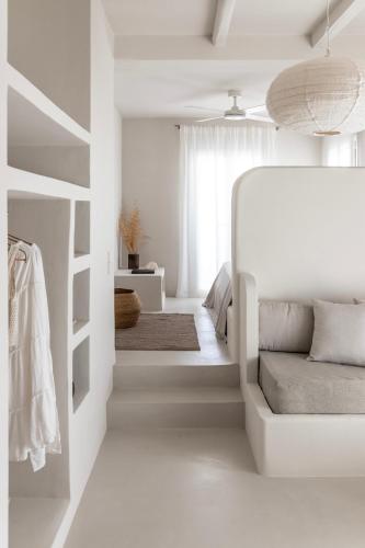 a white bedroom with a bed and a window at Om Living Milos in Pollonia