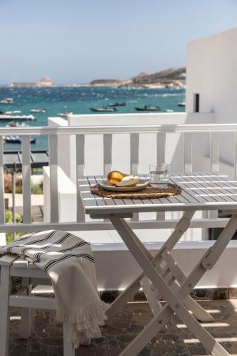 a white table with a plate of food on a balcony at Om Living Milos in Pollonia