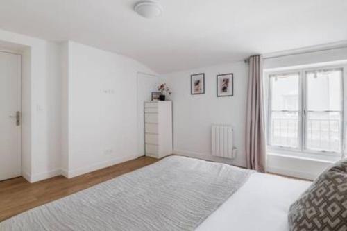 une chambre blanche avec un lit et une fenêtre dans l'établissement Cosy flat Grand boulevard 4 pers, à Paris