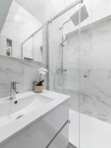 une salle de bain blanche avec une douche et un lavabo dans l'établissement Cosy flat Grand boulevard 4 pers, à Paris