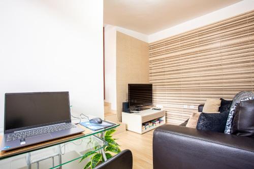 a living room with a laptop computer on a glass desk at Casa da Avó in Machico
