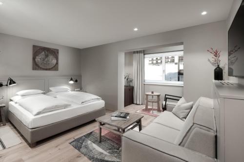 a bedroom with a bed and a living room at Hotel Rigele Royal Superior in Obertauern