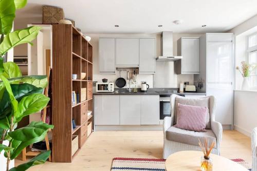 a kitchen with white cabinets and a chair and a table at Large Luxury Studio in Heart of Richmond in Richmond