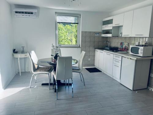 a kitchen with white cabinets and a table and chairs at My Eden Bihać in Mahala