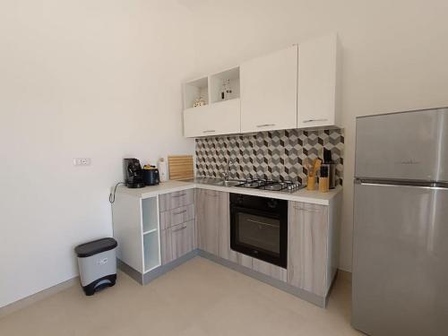 a kitchen with white cabinets and a stainless steel refrigerator at vacanza in Salento, La Terrazza in Surano
