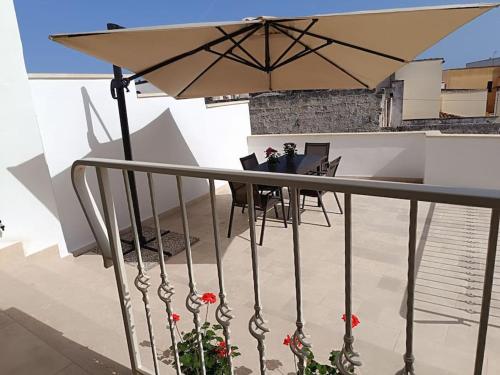 a balcony with a table and an umbrella at vacanza in Salento, La Terrazza in Surano
