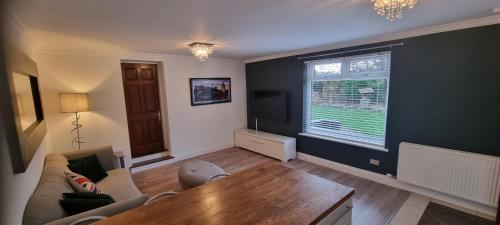 a living room with a couch and a large window at Laighdykes Guest Cottage in Saltcoats