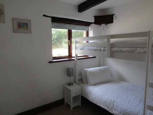 ein Schlafzimmer mit zwei Etagenbetten und einem Fenster in der Unterkunft Hazel Cottage, Frithelstock in Frithelstock