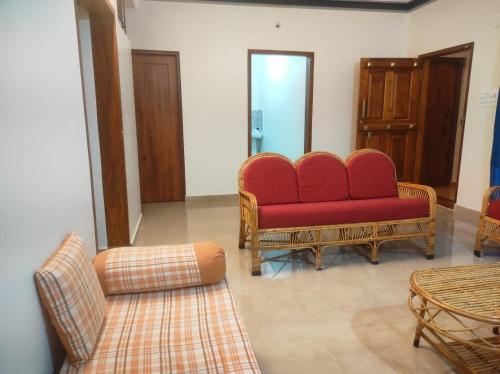a living room with two red chairs and a couch at Chikkus Misty Coorg homestay in Kushālnagar