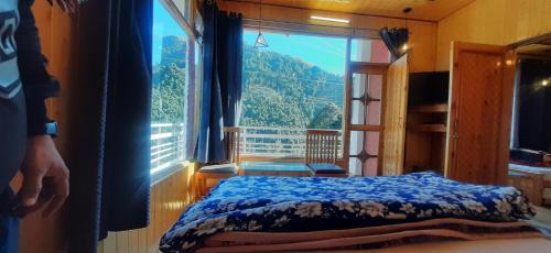 a bedroom with a bed and a large window at THE GROOVE GARDEN DHANOLTi in Dhanaulti