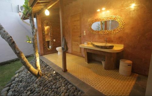 a bathroom with a sink and a mirror and a tree at Guesthouse Mooz in Canggu