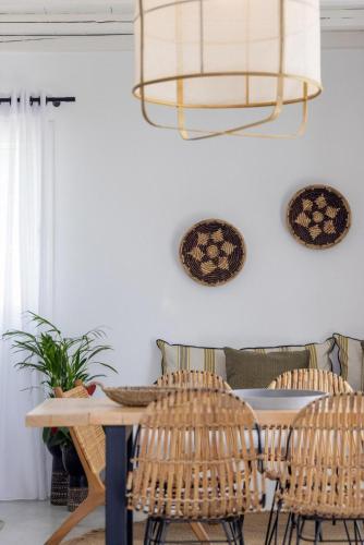 a dining room with a table and rattan chairs at Del Sol View Arnados Tinos in Arnados