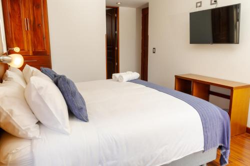 a bedroom with a white bed with a television on the wall at Samakwā Hotel Boutique in Paipa