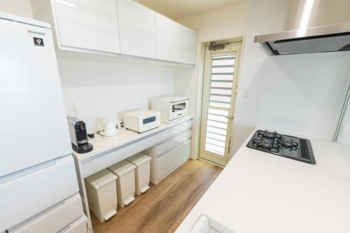 a kitchen with white cabinets and a stove top oven at 石垣島一棟貸し 潮 in Ishigaki Island