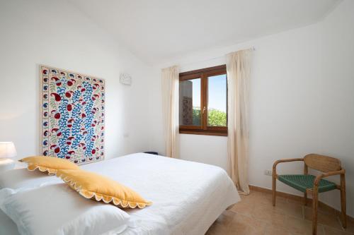 a bedroom with a bed and a chair and a window at Villaggio Perlacea - Your House in Sardinia in Golfo Aranci