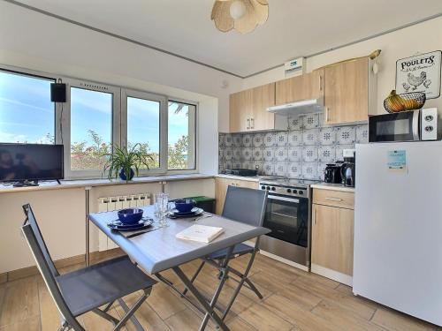 a kitchen with a table and a white refrigerator at Gite Villa Morgane - A 250 m de la plage de Pentrez in Saint-Nic