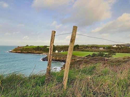 a fence on top of a hill next to the ocean at Gite Villa Morgane - A 250 m de la plage de Pentrez in Saint-Nic