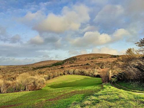 a green golf course with a hill in the background at Gite Villa Morgane - A 250 m de la plage de Pentrez in Saint-Nic