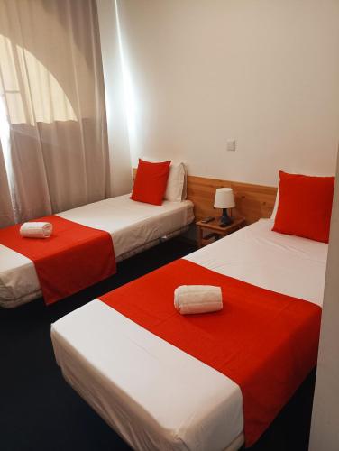 a room with two beds with red and white sheets at Al-Xelb guesthouse in Silves