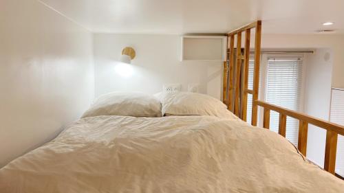 - un lit avec deux oreillers dans une chambre blanche dans l'établissement Charme Cosy au Cœur de Paris, à Paris