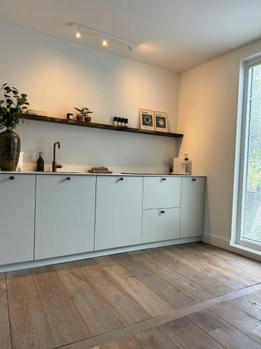 a kitchen with white cabinets and a wooden floor at De Wilden Ezel in Mol