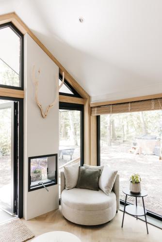 a living room with a couch and large windows at Tiny House Veluwse Vlucht in Stroe