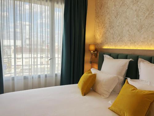 a bedroom with a bed with yellow and white pillows at Hôtel Oden Paris Ivry in Ivry-sur-Seine