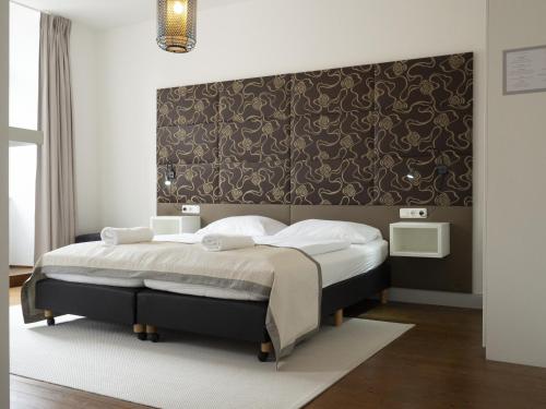 a bedroom with a large bed with a black headboard at Hotel Lekker in Neumagen-Dhron