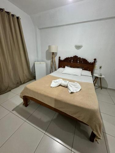 a bedroom with a bed with a robe on it at Hotel Olivier in Três Rios
