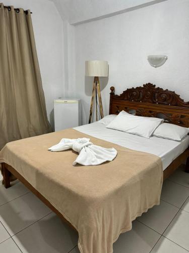 a bed with two white towels on top of it at Hotel Olivier in Três Rios
