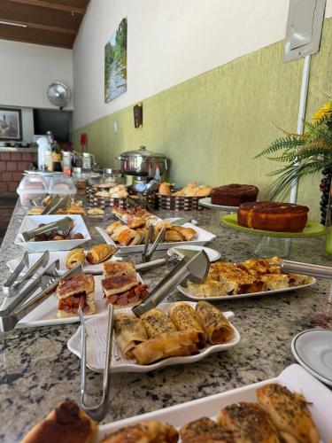 a buffet with many plates of food on a table at Hotel Olivier in Três Rios