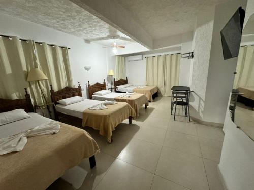 a hotel room with two beds and a table at Hotel Olivier in Três Rios