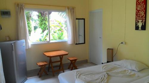 a bedroom with a bed and a table and a window at Aathid Garden Khao Lak in Khao Lak