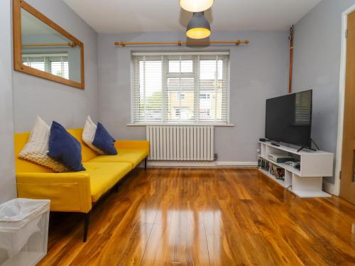 a living room with a yellow couch and a flat screen tv at The Bullseye in Stonehouse