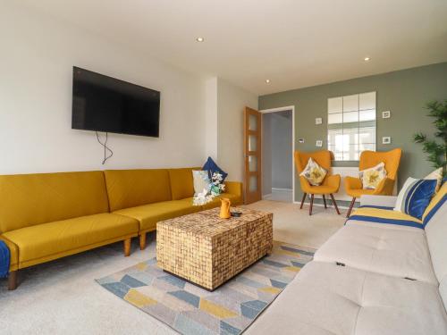 a living room with a yellow couch and a tv at The Bullseye in Stonehouse