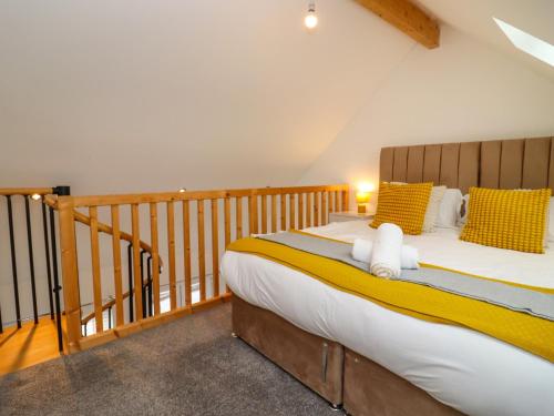 a bedroom with a large bed with yellow and white pillows at The Bullseye in Stonehouse