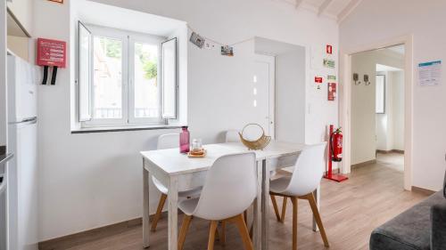 a kitchen and dining room with a white table and chairs at Cozy Retreat with Patio Near Sintra by LovelyStay in Colares