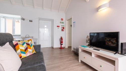 a living room with a tv and a couch at Cozy Retreat with Patio Near Sintra by LovelyStay in Colares