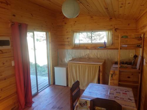a kitchen with a table in a wooden cabin at Chalets rustiques en pleine nature, L'ARCHIPEL in Punta Del Diablo