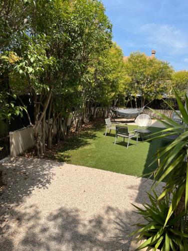 a garden with two park benches and trees at Maison 6 personnes 3 chambres Aéroport-Plages in Marignane